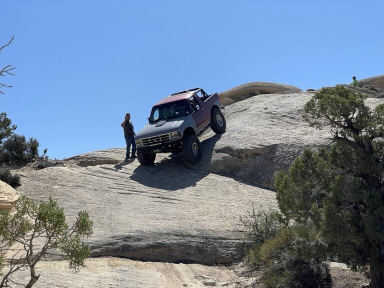 Bronco on a rocky outcrop with a person standing nearby