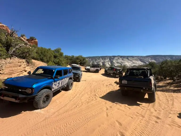 Blue Bronco and other vehicles on a sandy desert trail