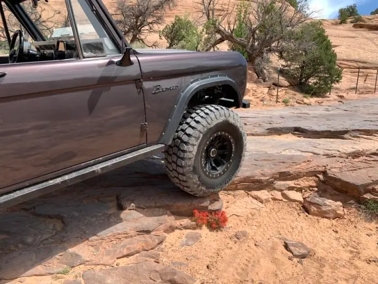 Early Bronco climbing a rocky ledge on a red rock trail