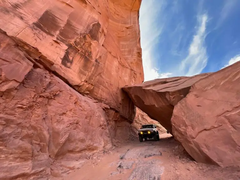 Small Bronco beneath a red sandstone arch