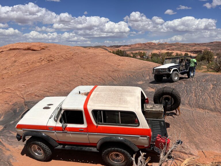 White and red early Bronco on slickrock with another Bronco in the distance